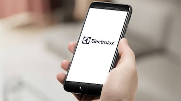 En hand håller en mobiltelefon med Electrolux app synlig på skärmen.